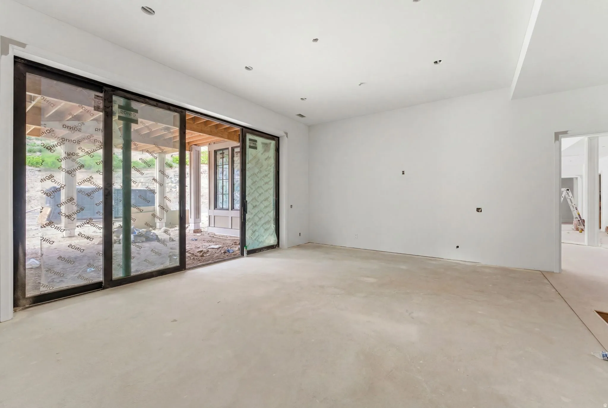 Expansive interior space featuring a large sliding glass door, recessed ceiling lighting, and a neutral color palette