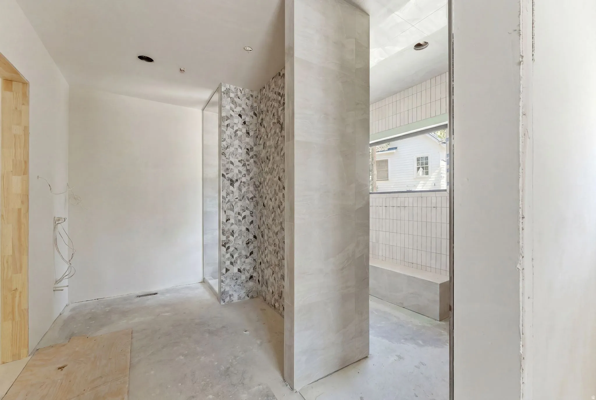 Walk-in shower with decorative tiled wall, full-height glass panel, and built-in bench
