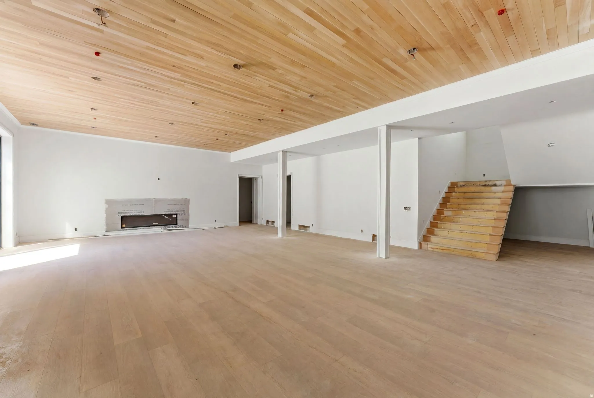 Spacious room featuring wood-finish flooring, a complementary wood-plank ceiling, and a built-in fireplace