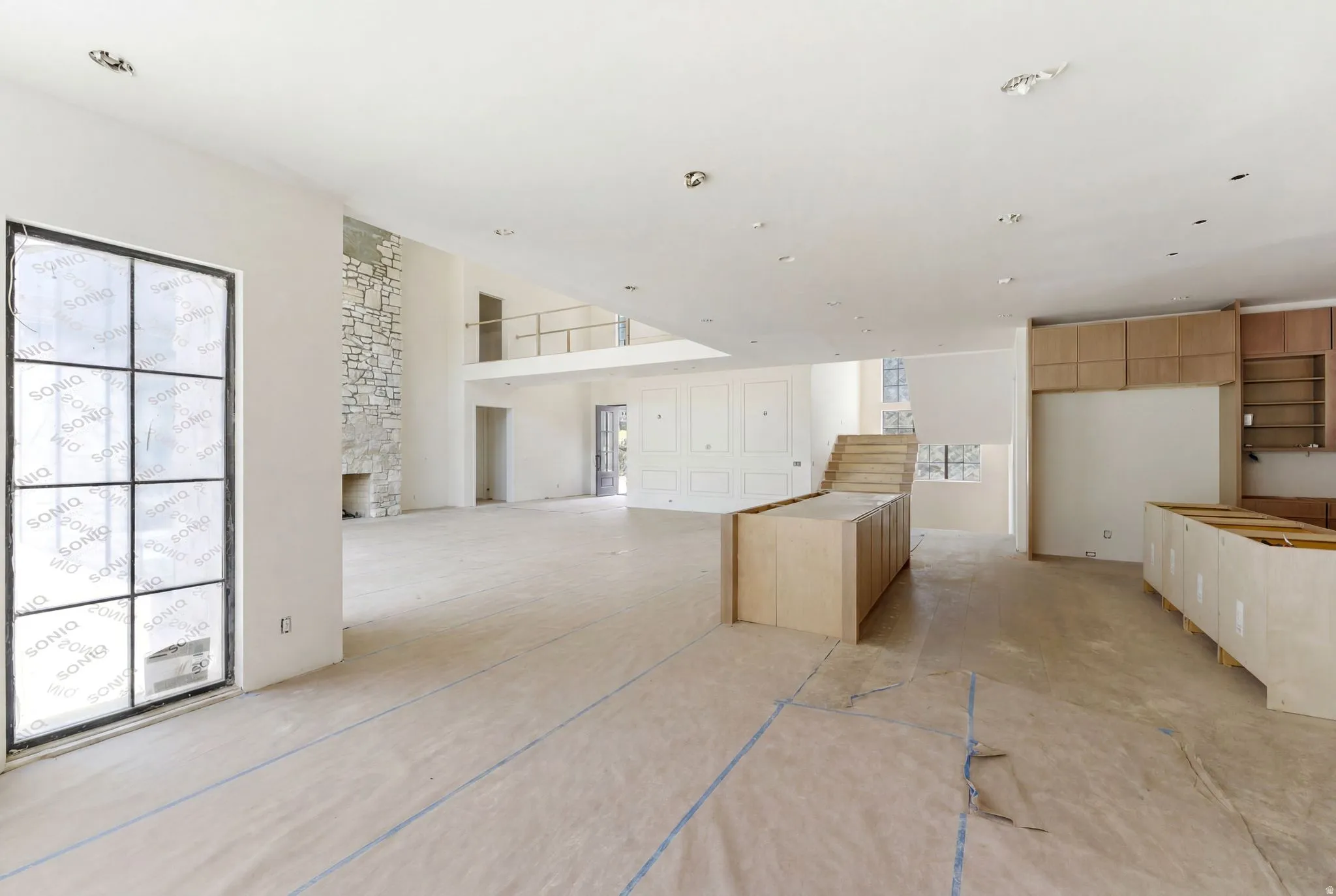 Open-concept living area featuring a stone-clad fireplace and large multi-pane windows