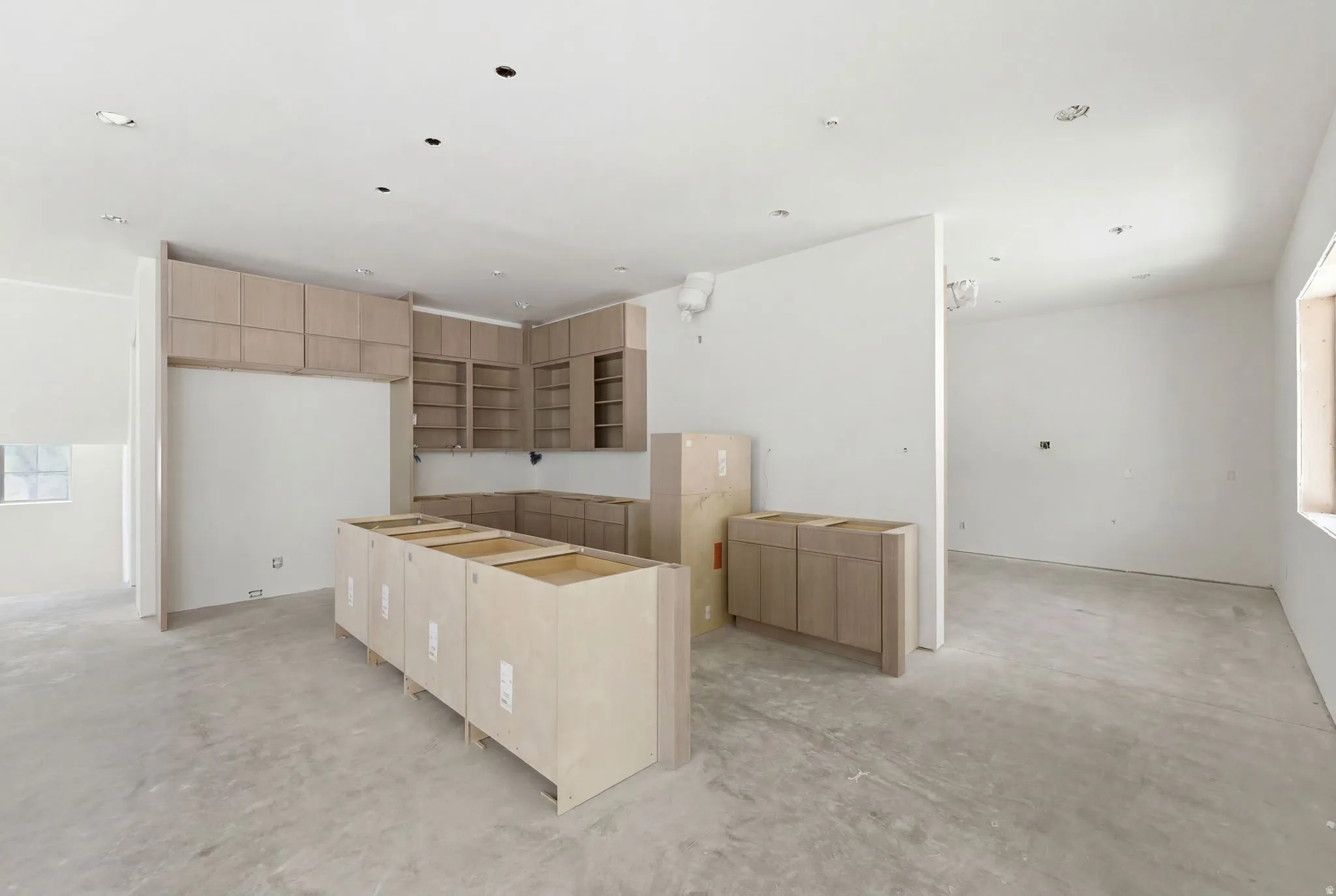Kitchen featuring light wood-finish cabinetry, a central island base, recessed lighting, and a window