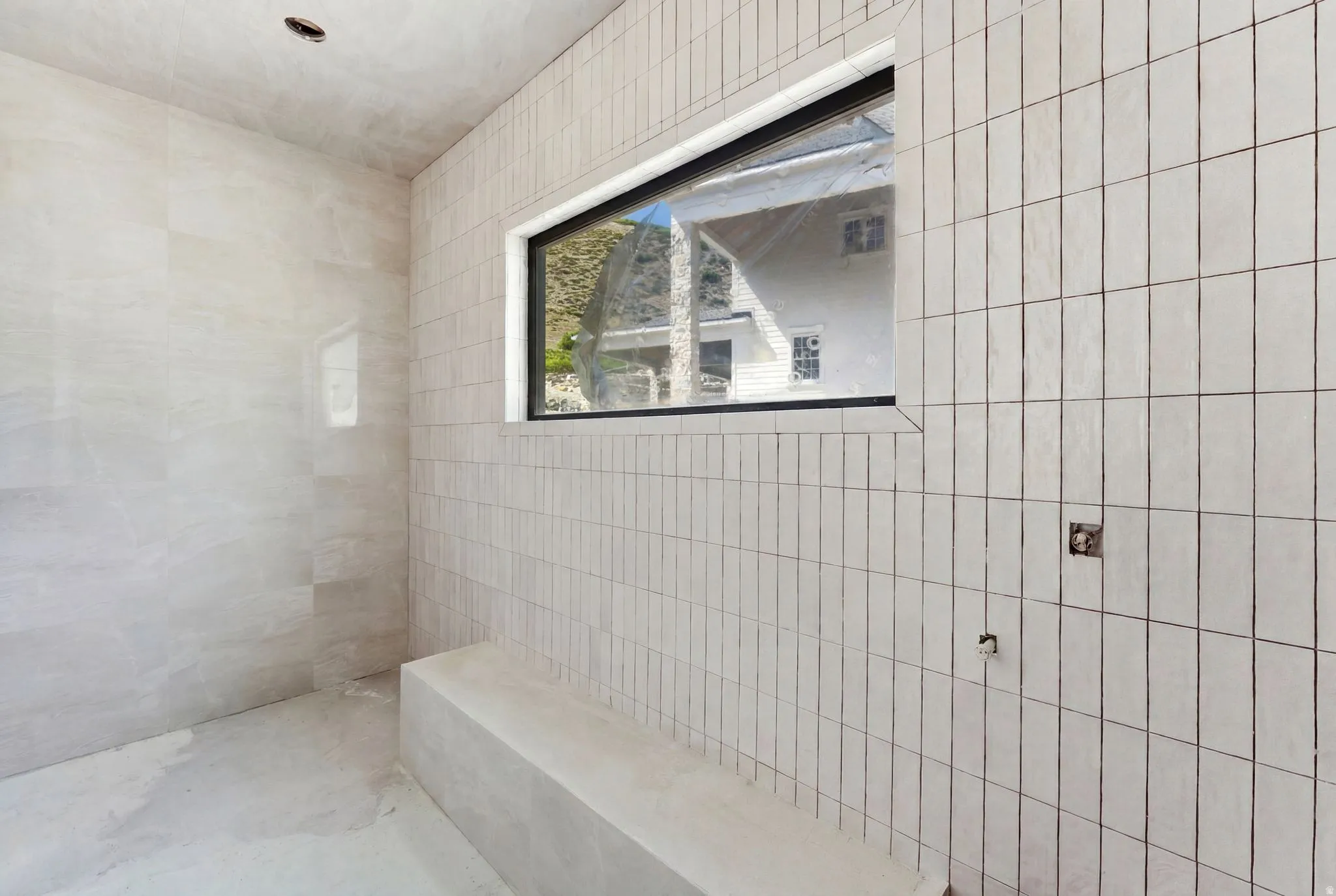 Tiled shower enclosure featuring vertical stacked rectangular tiles and a horizontal black-framed window