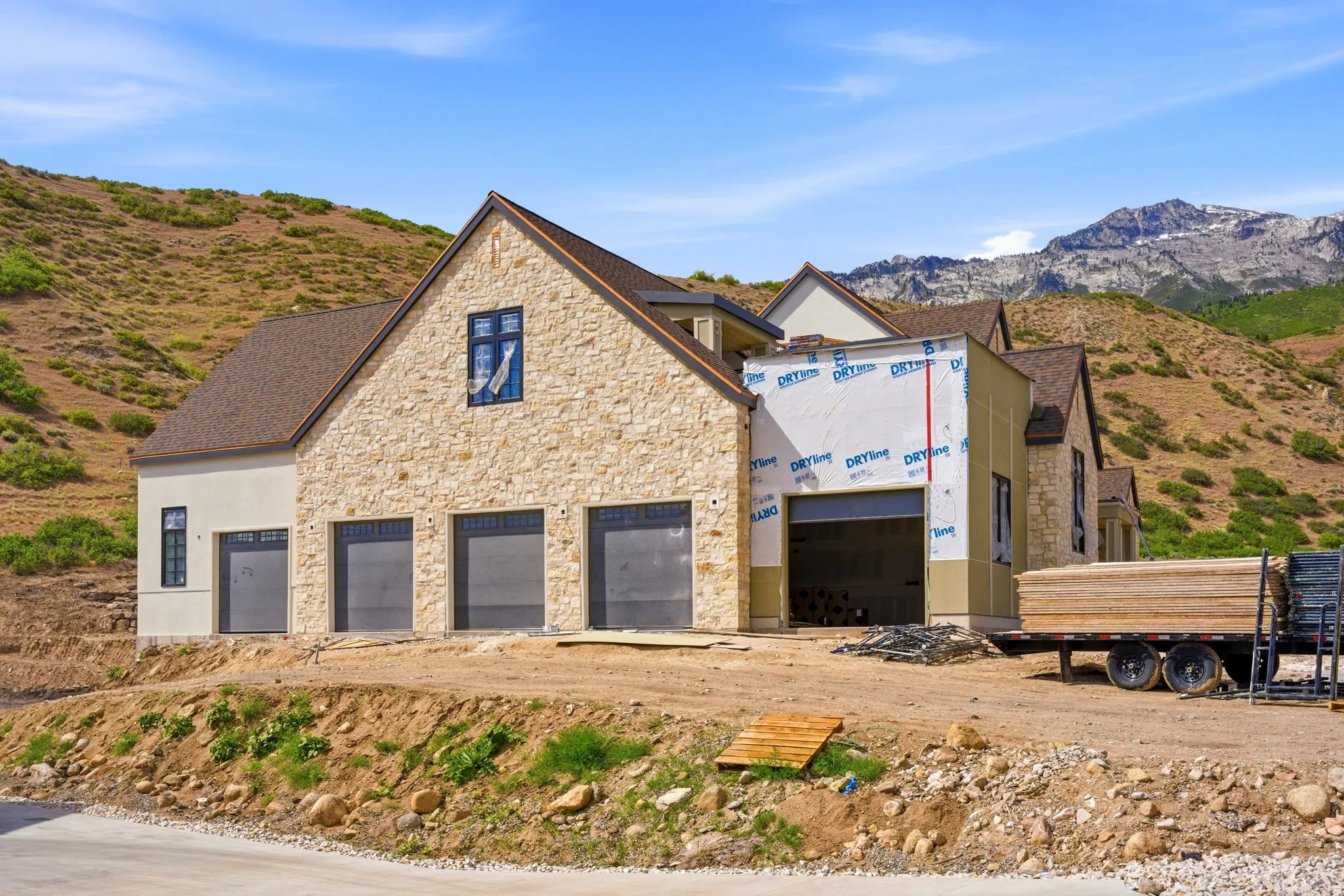 Contemporary stone and stucco exterior with multiple garage bays, dark framed windows, and a multi-level roofline