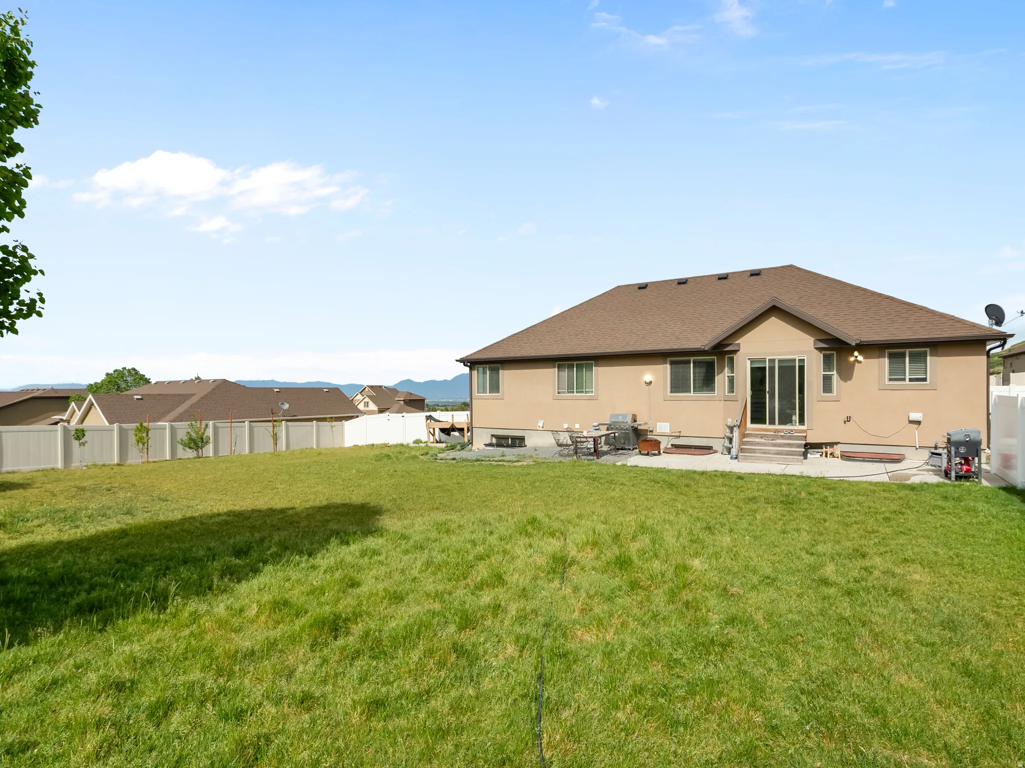 Expansive backyard featuring a manicured lawn, a full vinyl fence, and a patio area