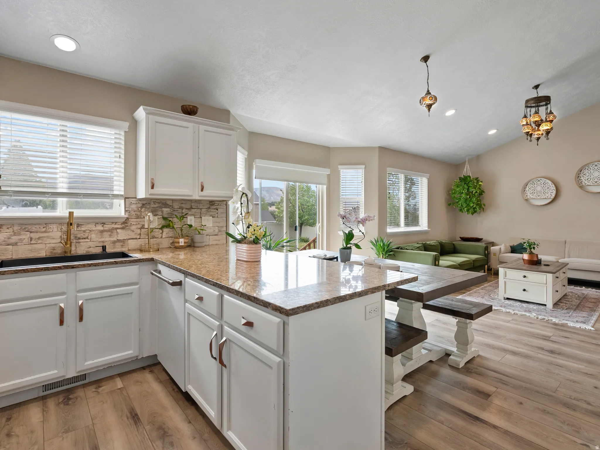Kitchen island with granite countertops, integrated dining table, and white cabinetry