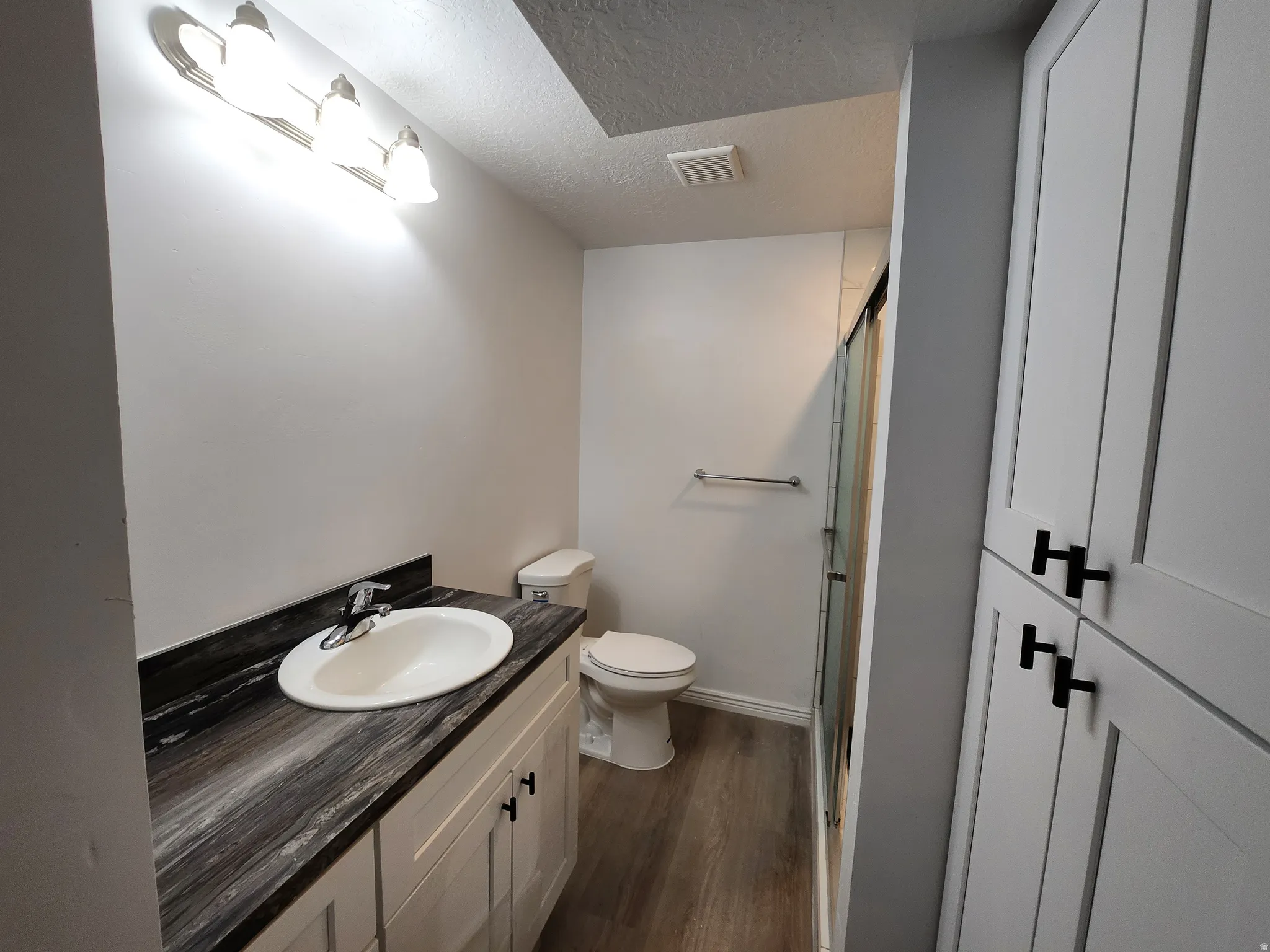 Bathroom featuring a white vanity with a dark marble-look countertop and under-mount sink