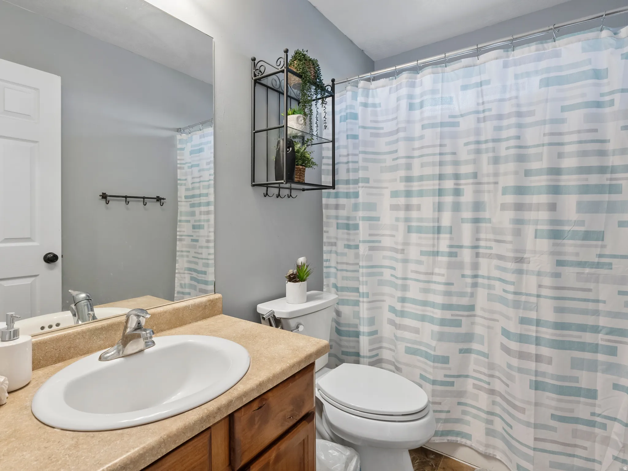 Bathroom featuring a vanity with an integrated sink, a large wall mirror, and a full shower with a patterned curtain