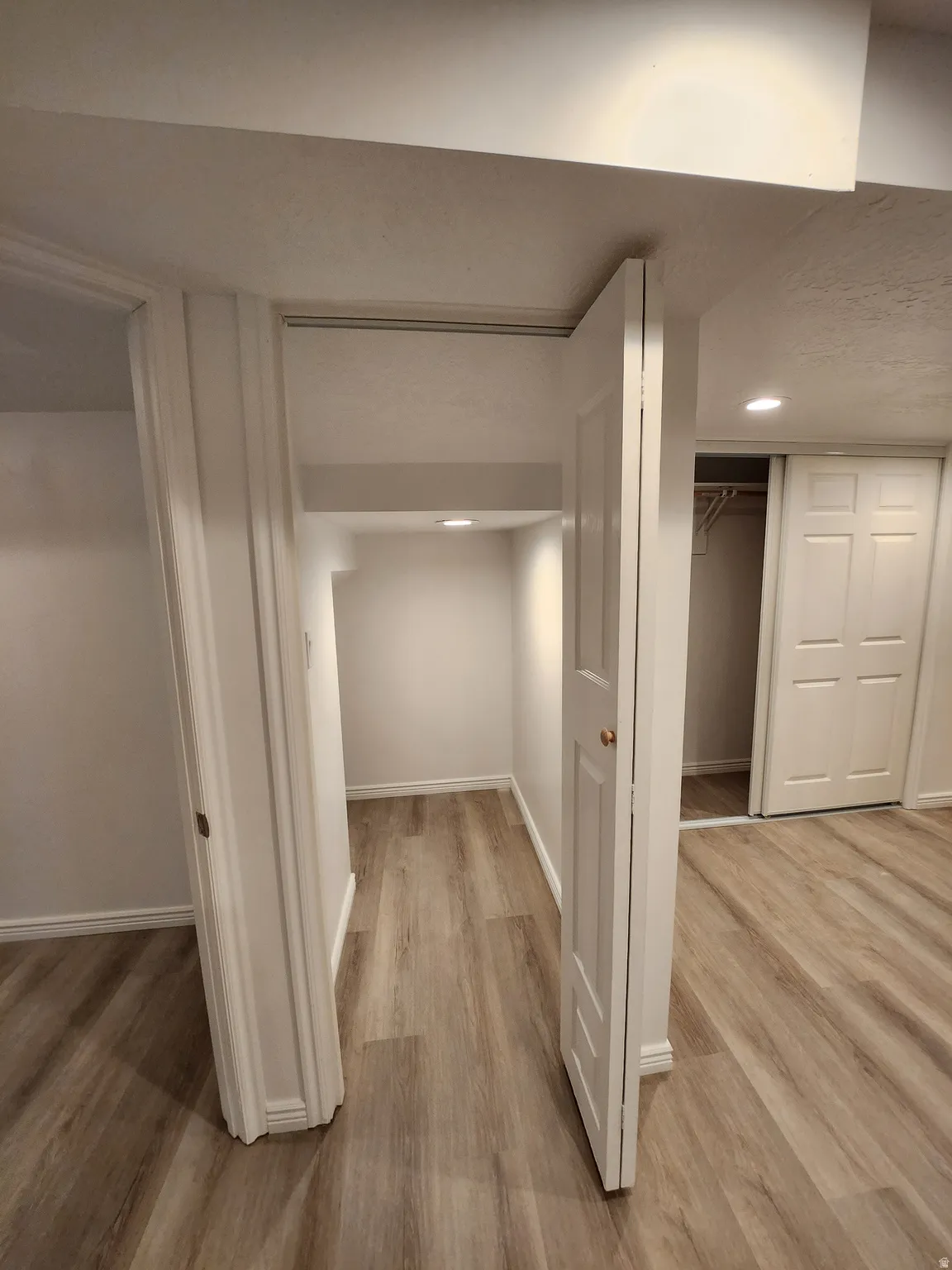 Recessed ceiling lighting illuminates a deep interior space with wood-finish flooring and white baseboards