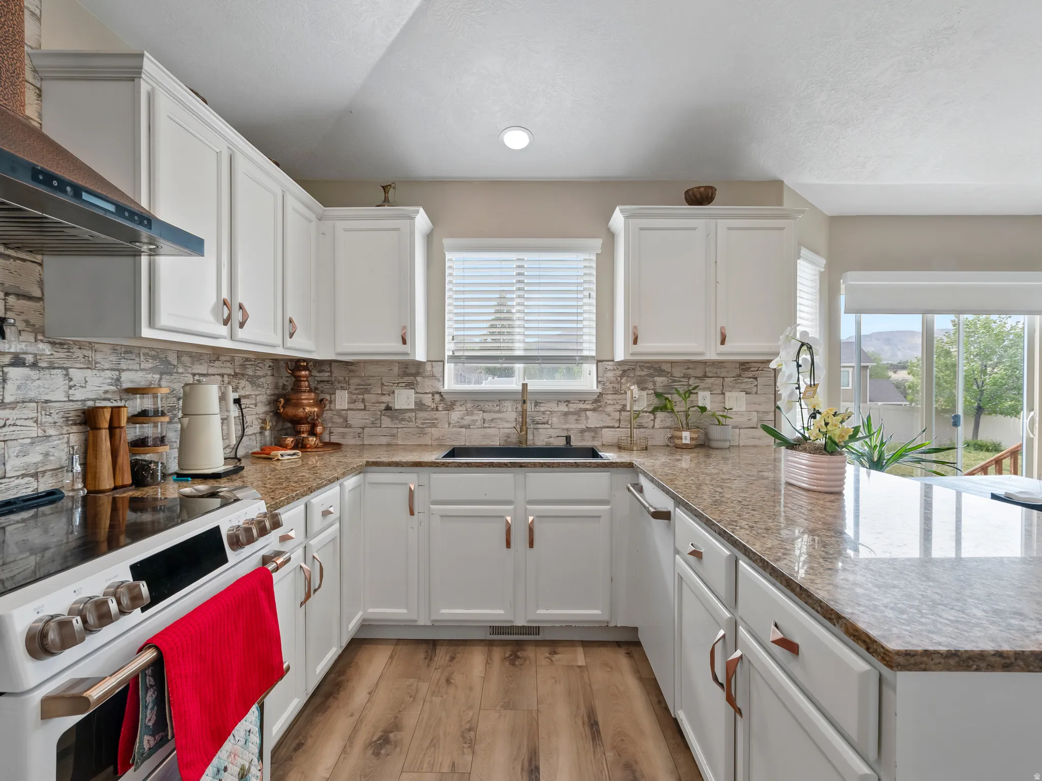 U-shaped kitchen with white cabinetry and wood-finish flooring
