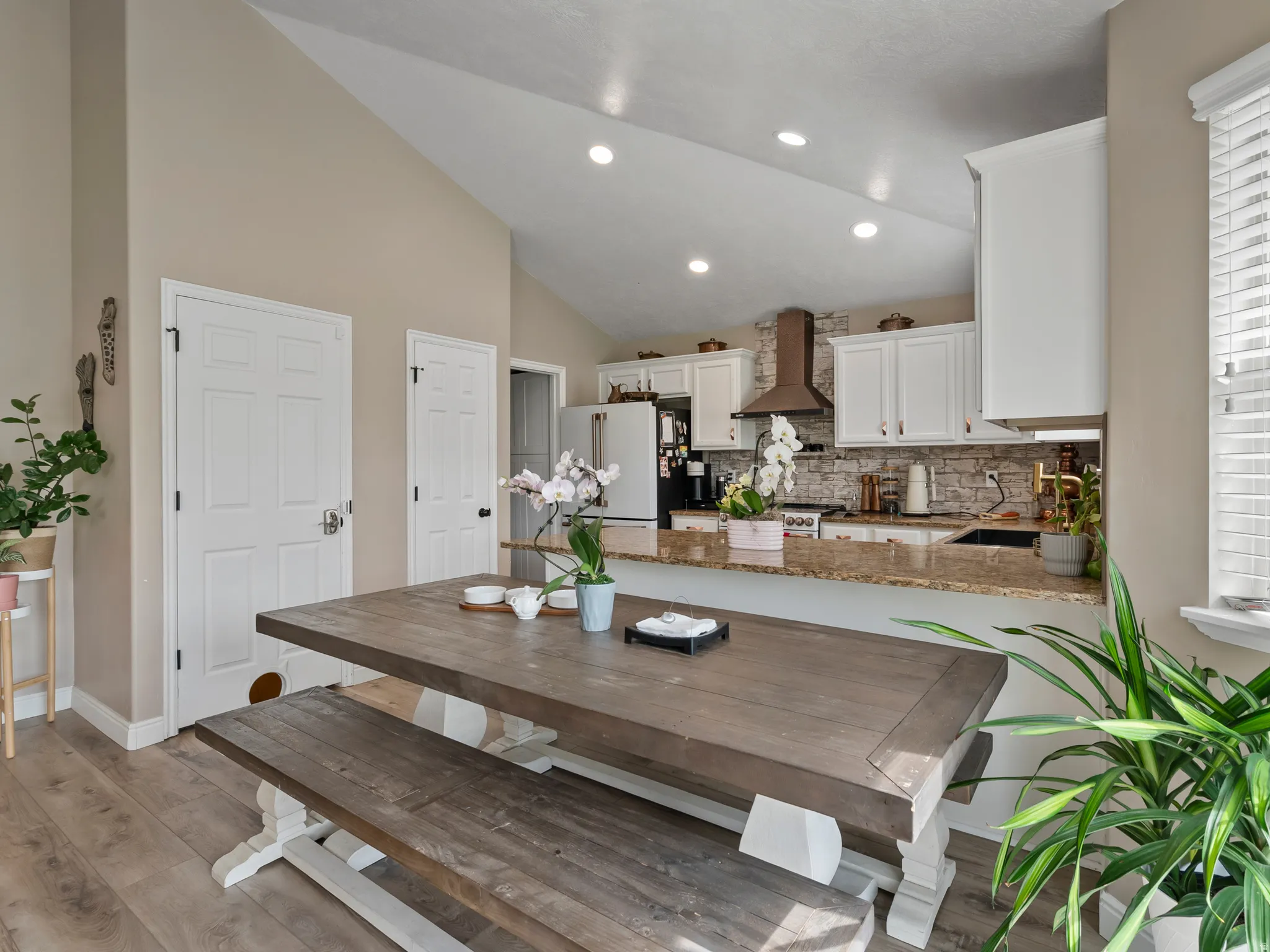Open-concept dining and kitchen area featuring a vaulted ceiling and recessed lighting
