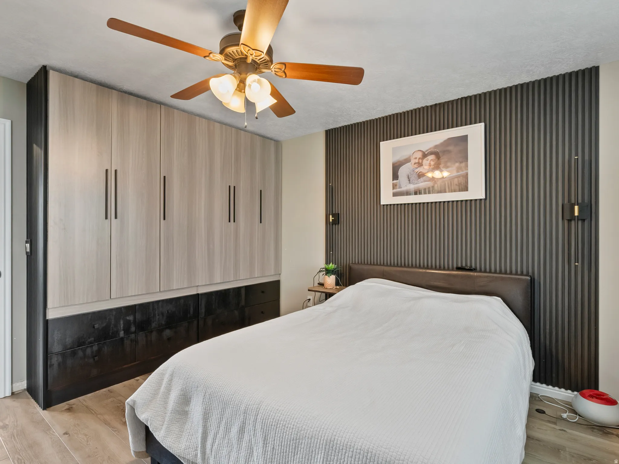 Wall-mounted storage cabinetry with wood-finish doors and dark-toned base drawers, complemented by a textured accent wall