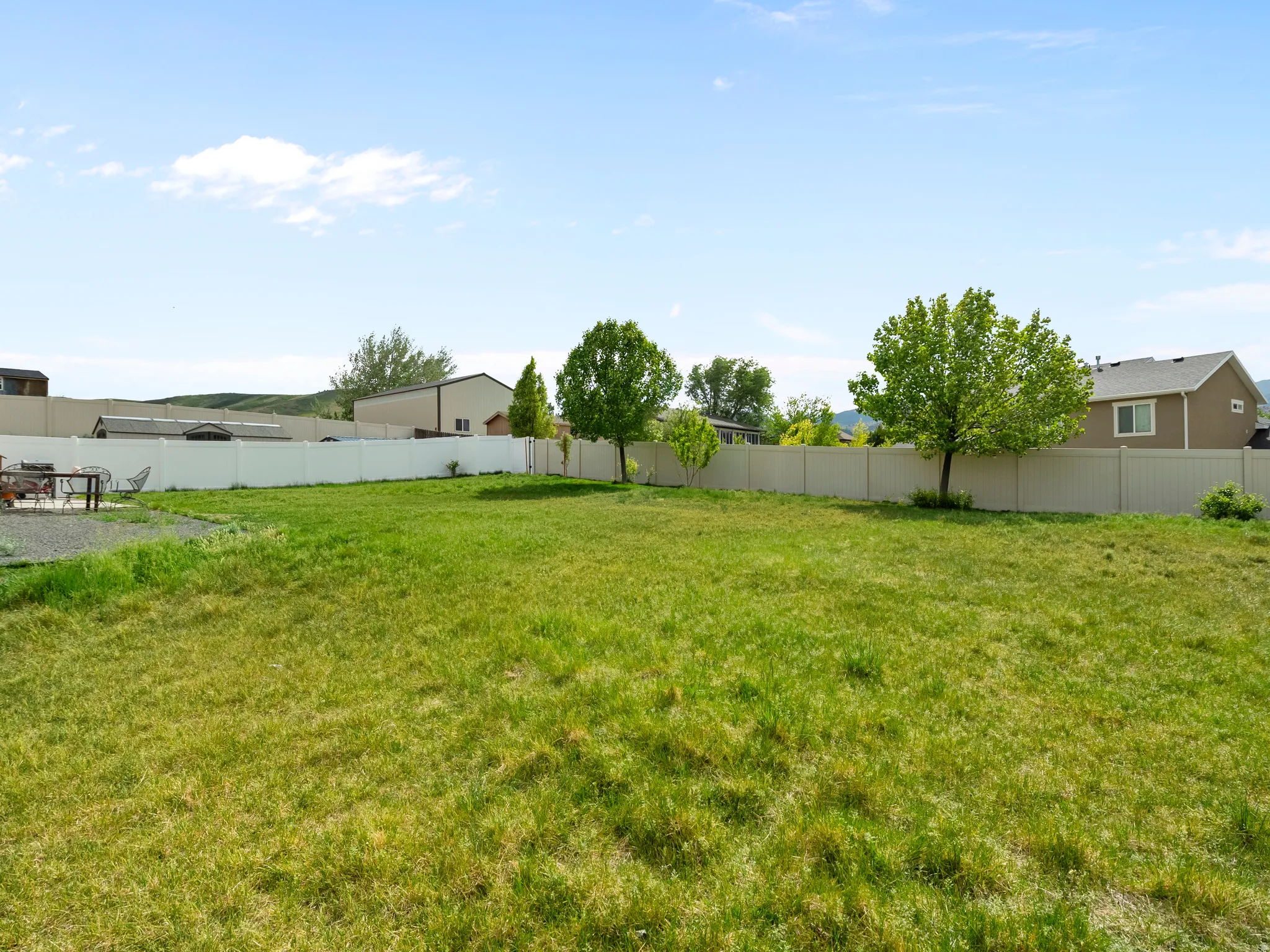 Expansive backyard with a large grass lawn, mature trees, and a full privacy fence