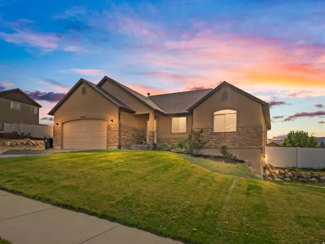 Stucco and stone facade home with an attached garage and front yard