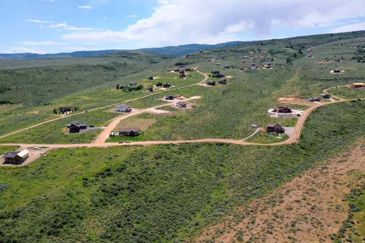 Expansive, undeveloped terrain featuring winding dirt roads and scattered residential properties, set against a backdrop of rolling hills and distant mountains