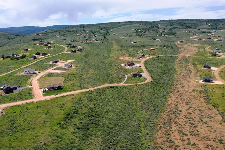 Expansive hillside property featuring scattered residences, winding unpaved roads, and varied topography