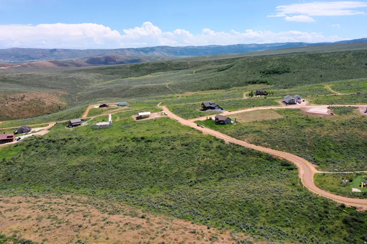 Expansive, undeveloped land featuring multiple residential structures and unpaved roads