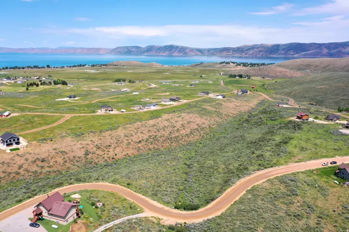 Expansive land parcels featuring established roads, scattered residential structures, and a prominent lake backdrop