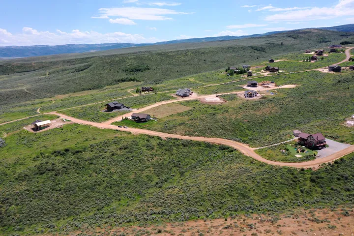 Expansive high-desert landscape featuring multiple properties with individual driveways and natural vegetation