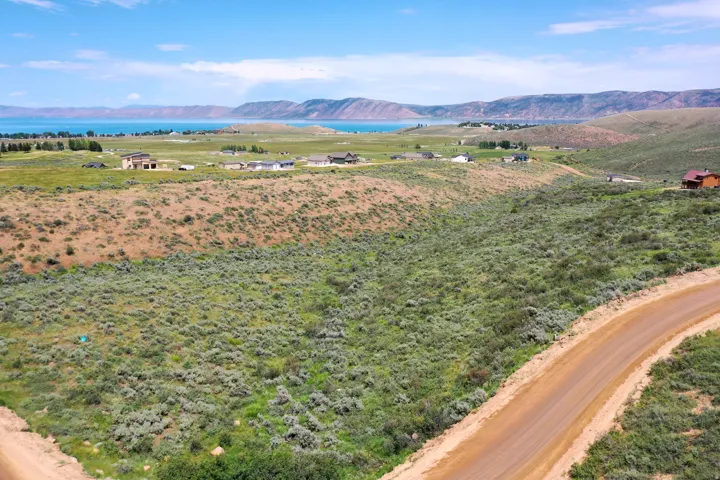 Expansive land parcel featuring natural shrubbery and a winding dirt road