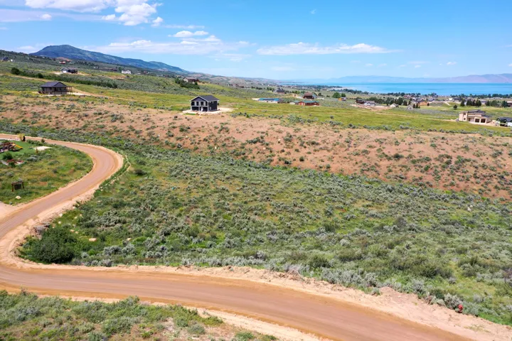 Expansive undeveloped land featuring a winding dirt road and distant lake and mountain scenery