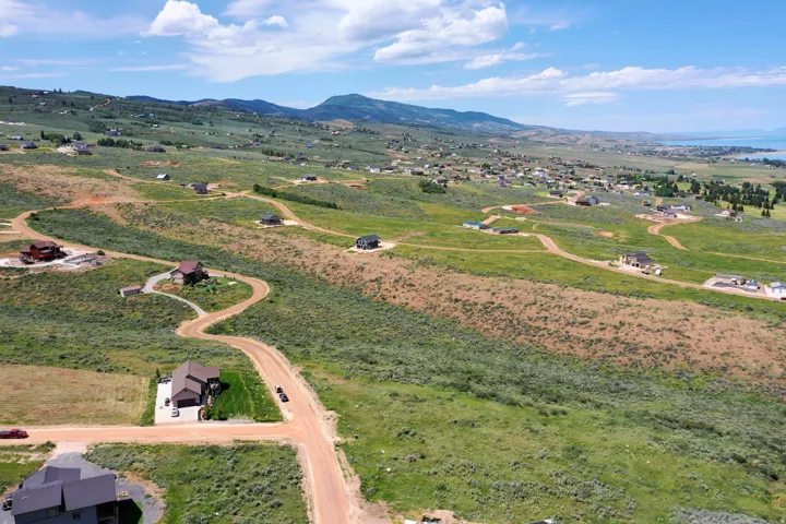 Expansive hillside landscape featuring multiple properties, unpaved roads, and distant mountains