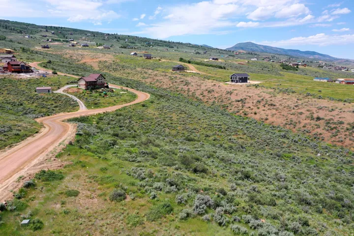 Expansive undeveloped land parcel featuring natural shrubbery and distant mountain scenery