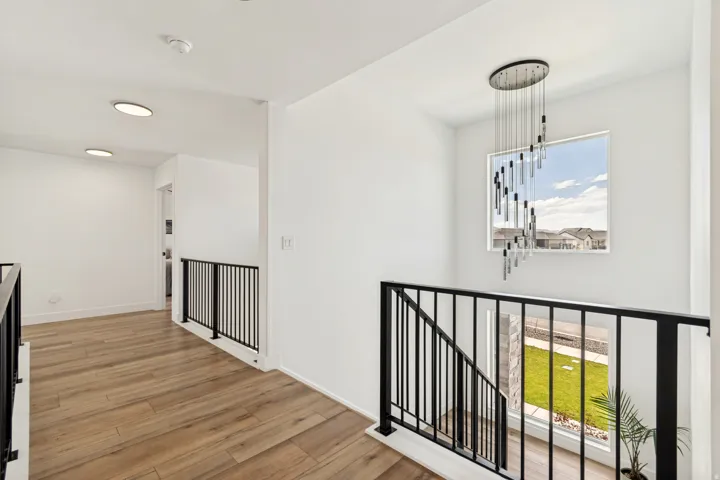 Upper-level hallway with wood-finish flooring, white walls, and recessed lighting