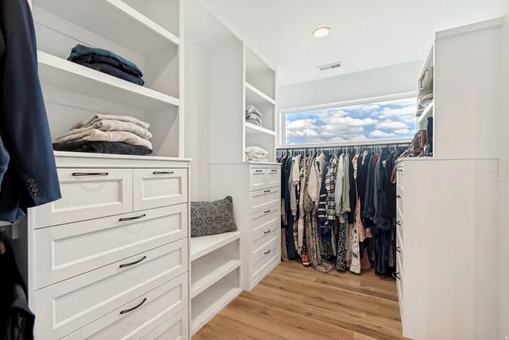 Custom closet featuring extensive built-in cabinetry, shelving, and hanging rods