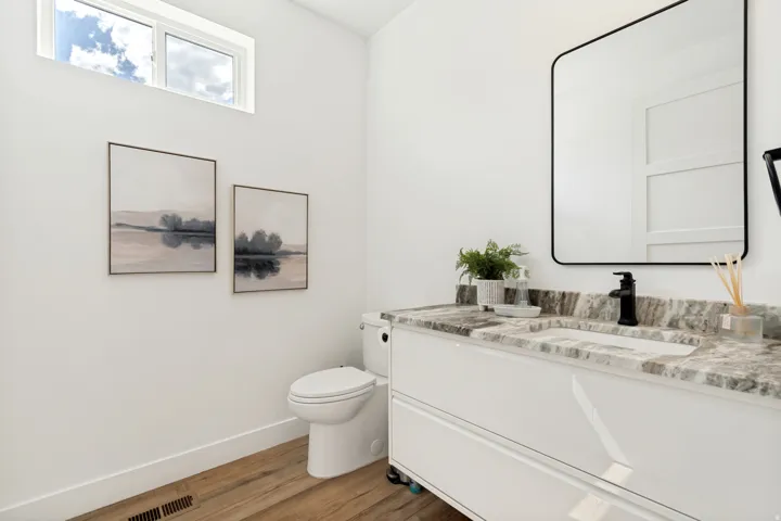 Bright bathroom featuring a contemporary vanity with a stone-finish countertop, integrated rectangular sink, and matte black faucet