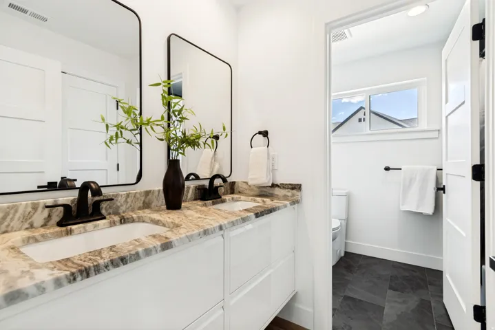 Double vanity featuring integrated sinks, a patterned countertop, and matte black fixtures