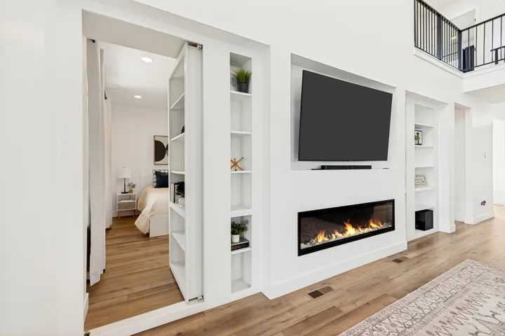 Open-concept living space with wood-finish flooring, a linear fireplace, and an integrated media wall