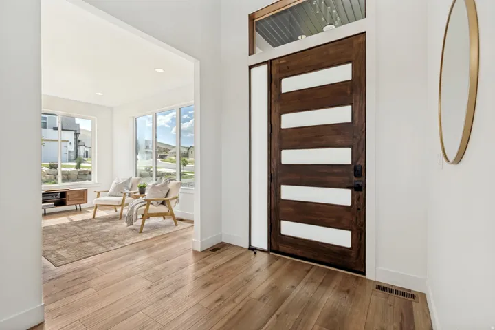 Rich wood-finish entry door with frosted glass panels and a transom window