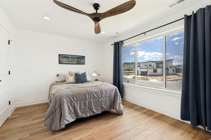 Room featuring a wide window with dark blue curtains and a modern wood-finish ceiling fan