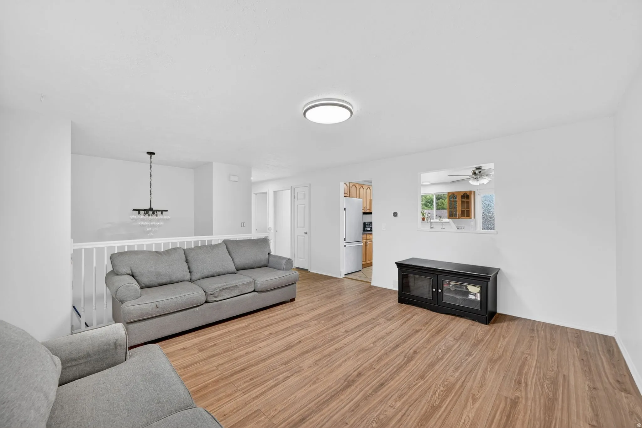 Bright living area featuring wood-finish flooring, white walls, and a contemporary flush-mount ceiling light