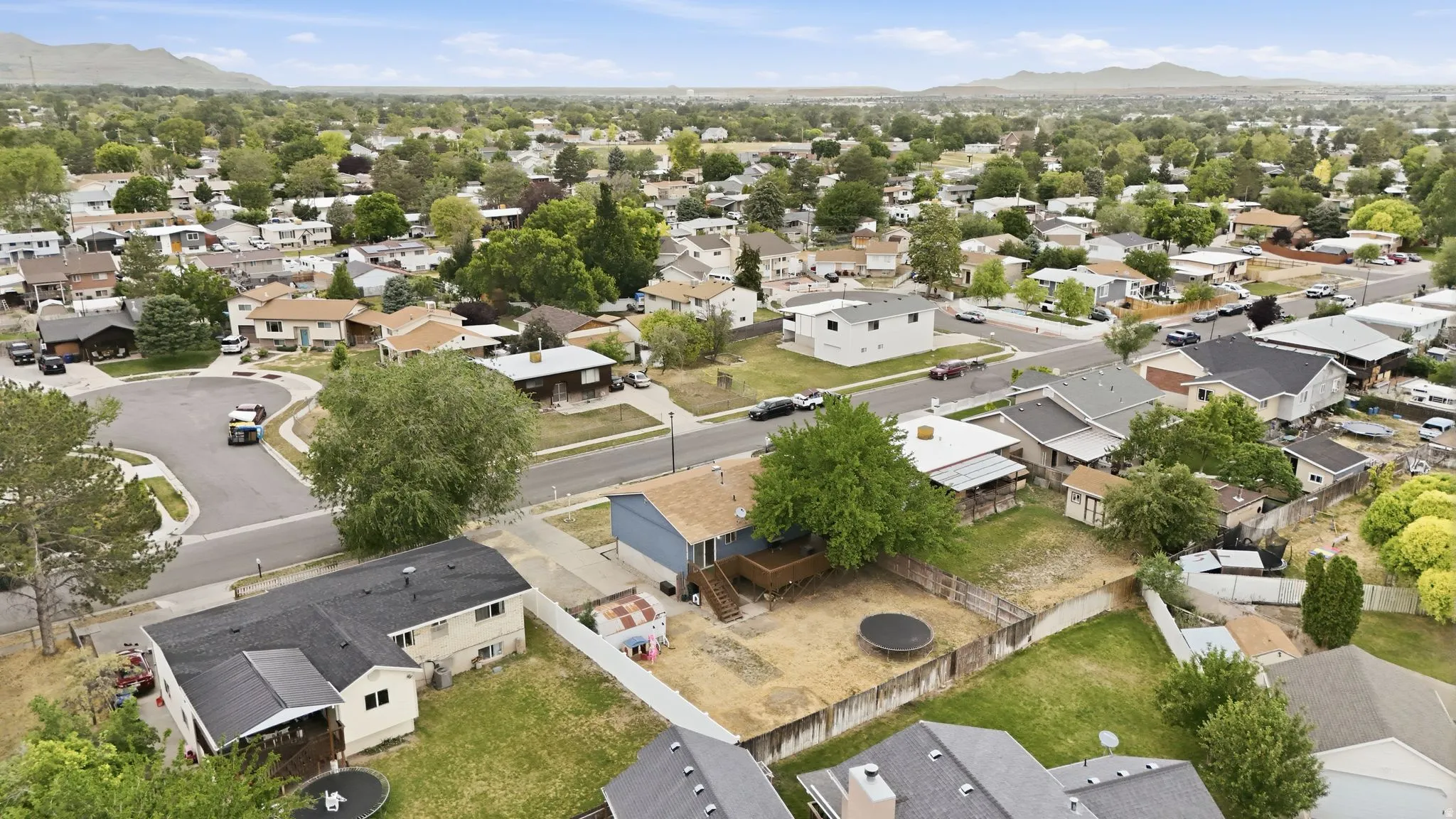 Suburban neighborhood setting with established tree canopy and distant mountain backdrop
