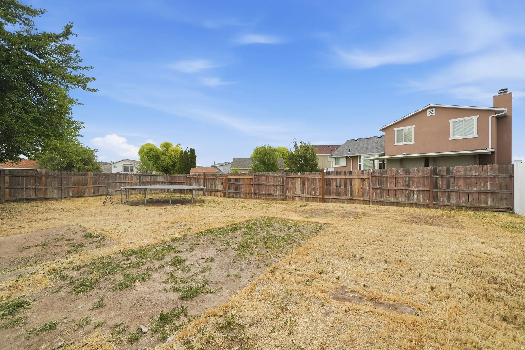Expansive backyard enclosed by a wood privacy fence