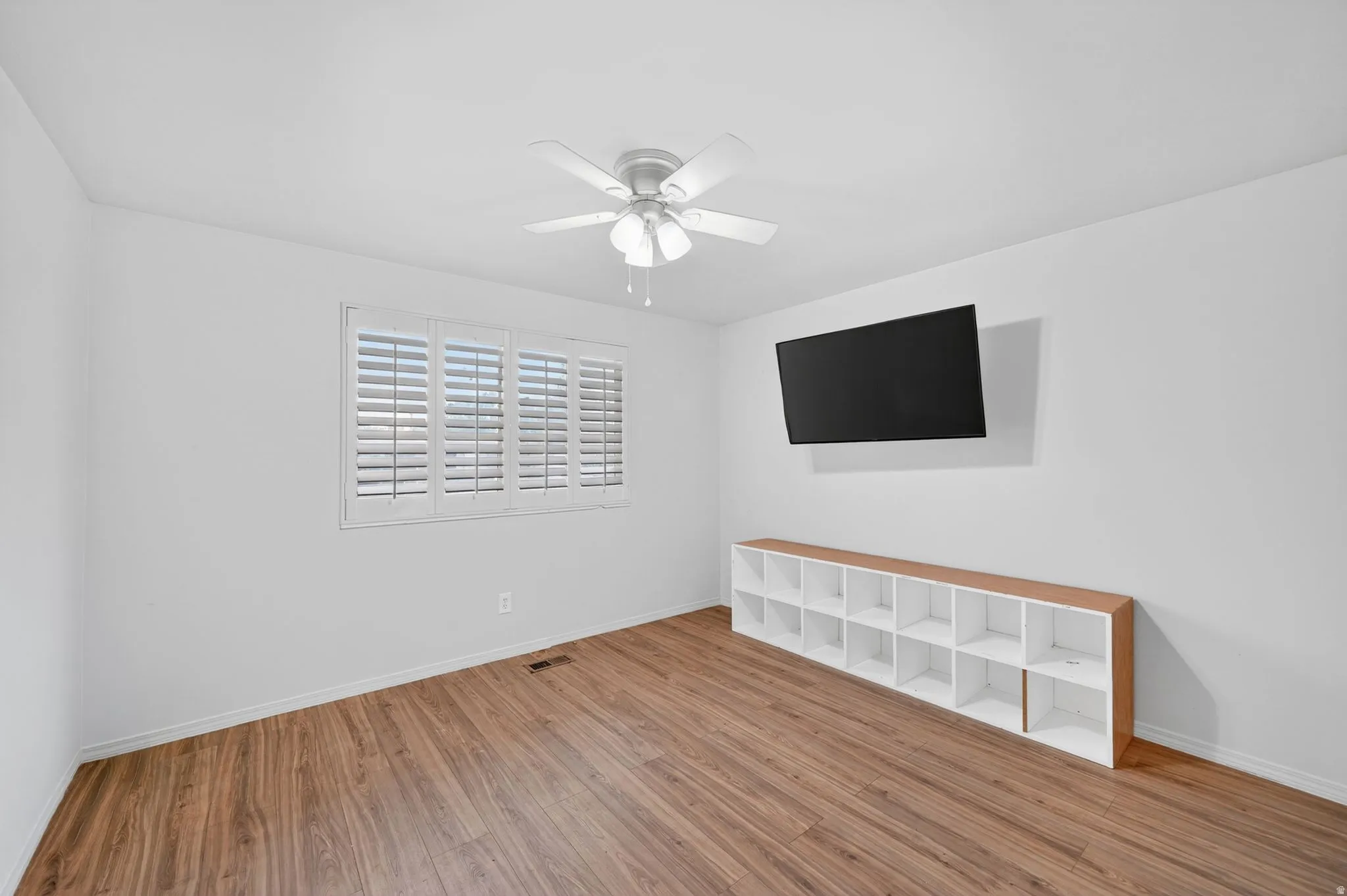 Bright room featuring wood-finish flooring and a ceiling fan