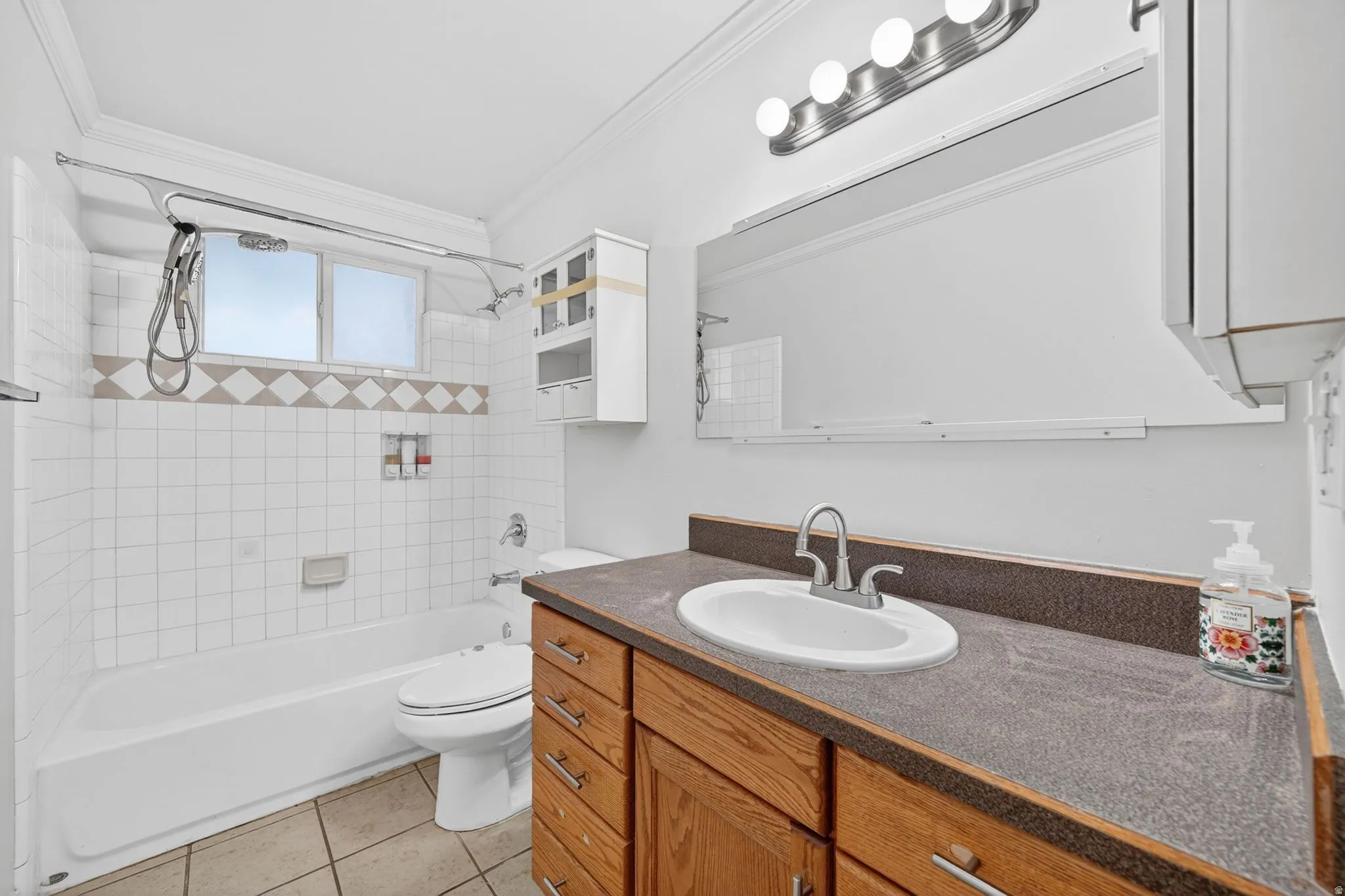 Bathroom featuring a wood-finish vanity with an integrated sink, a dark countertop, and a large wall-mounted mirror