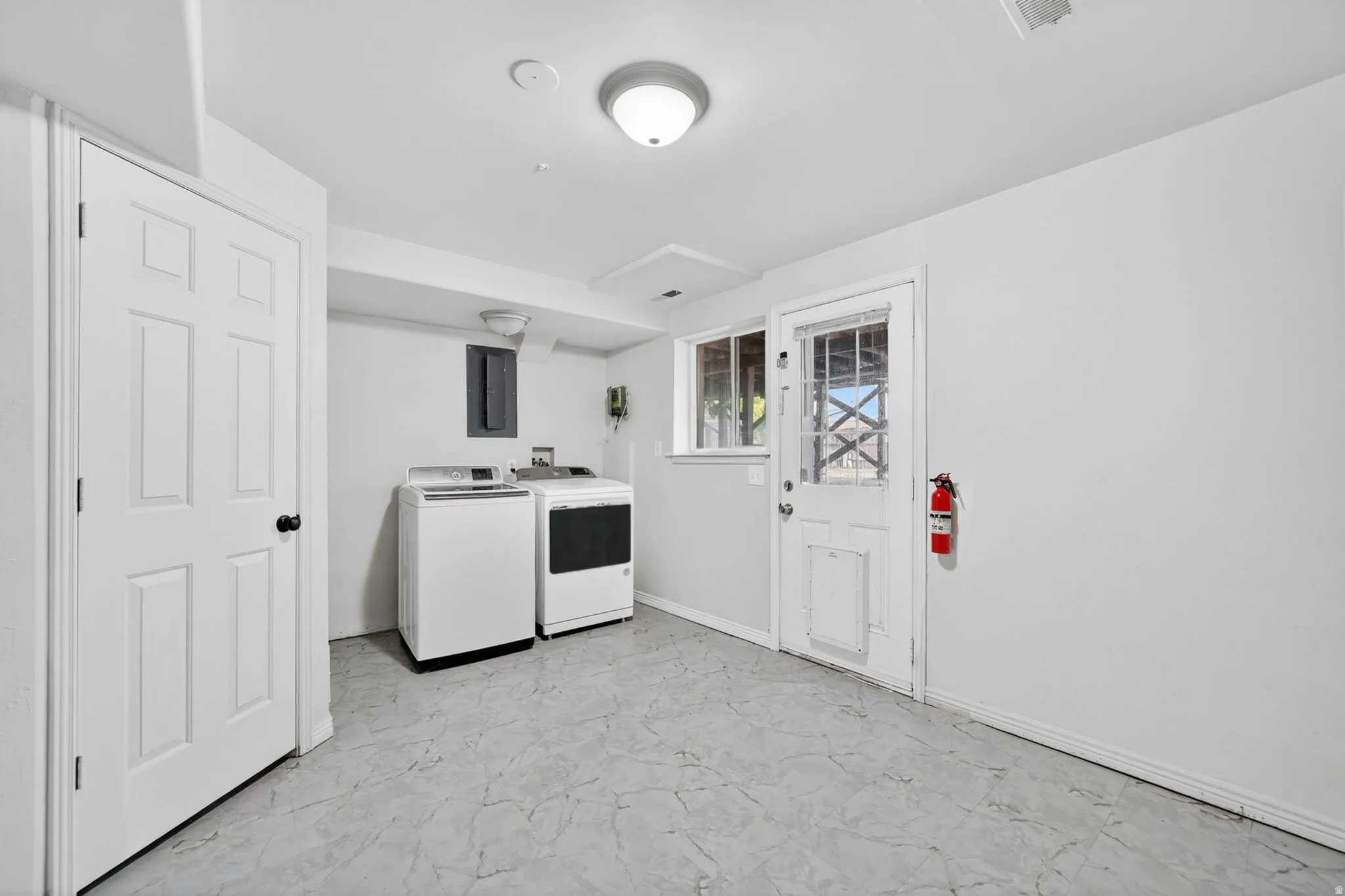 Dedicated utility room featuring light gray walls, patterned flooring, and a white six-panel interior door with black hardware