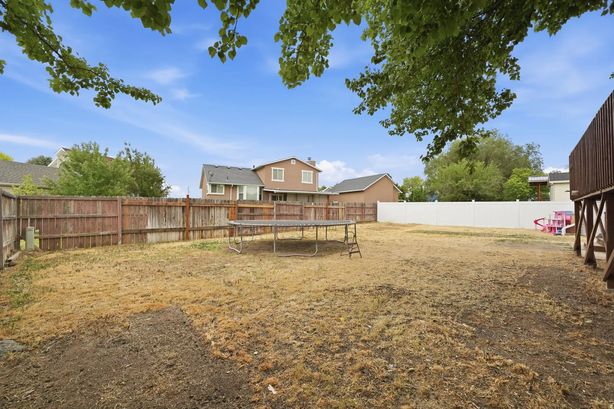 Expansive backyard featuring a combination of wood and white vinyl fencing
