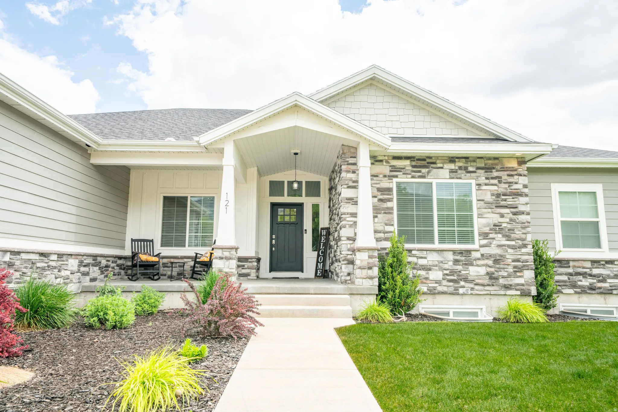 Contemporary residence featuring a covered front porch with stone and siding accents