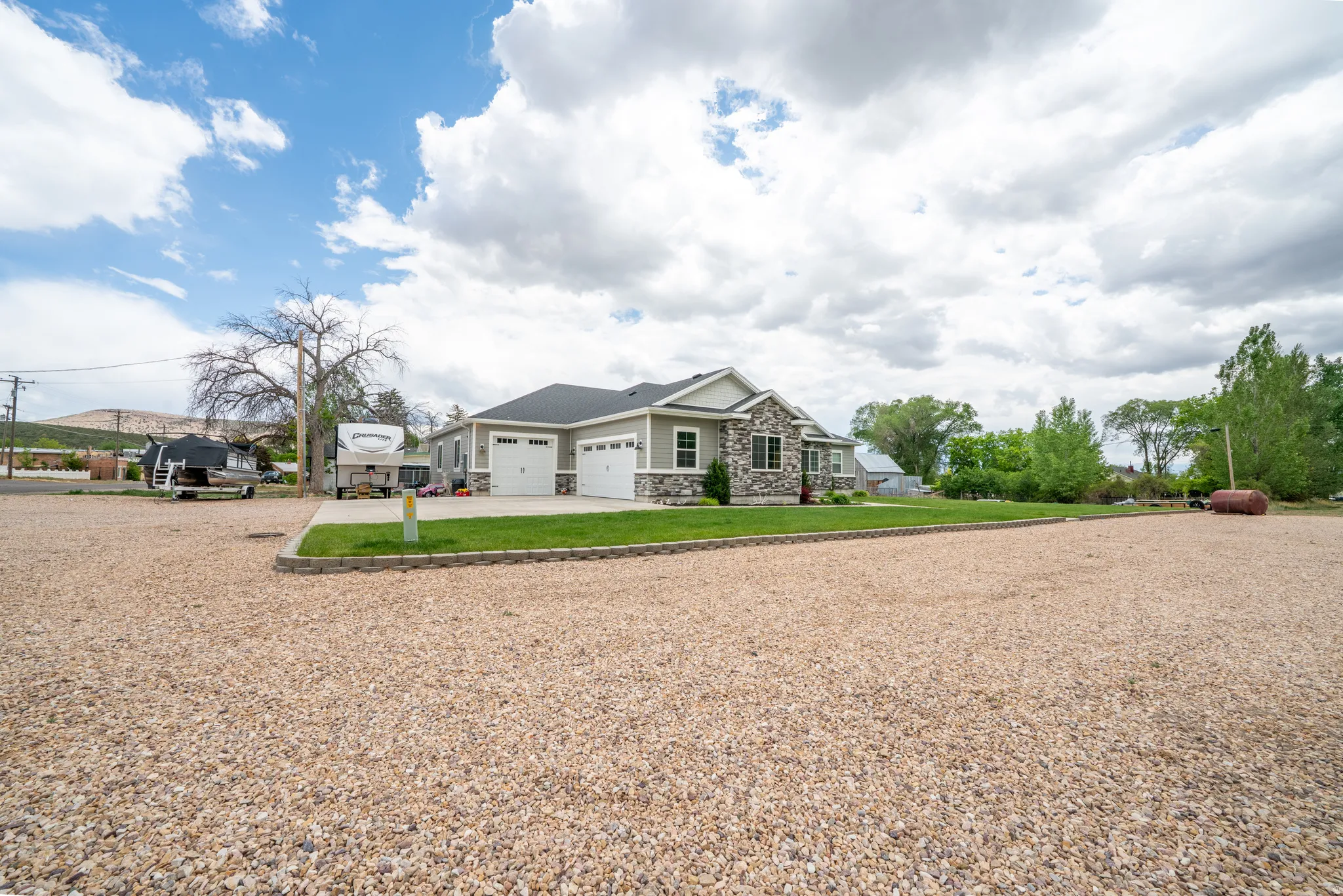 Ranch-style exterior with a three-car garage, stone façade accents, and light gray siding