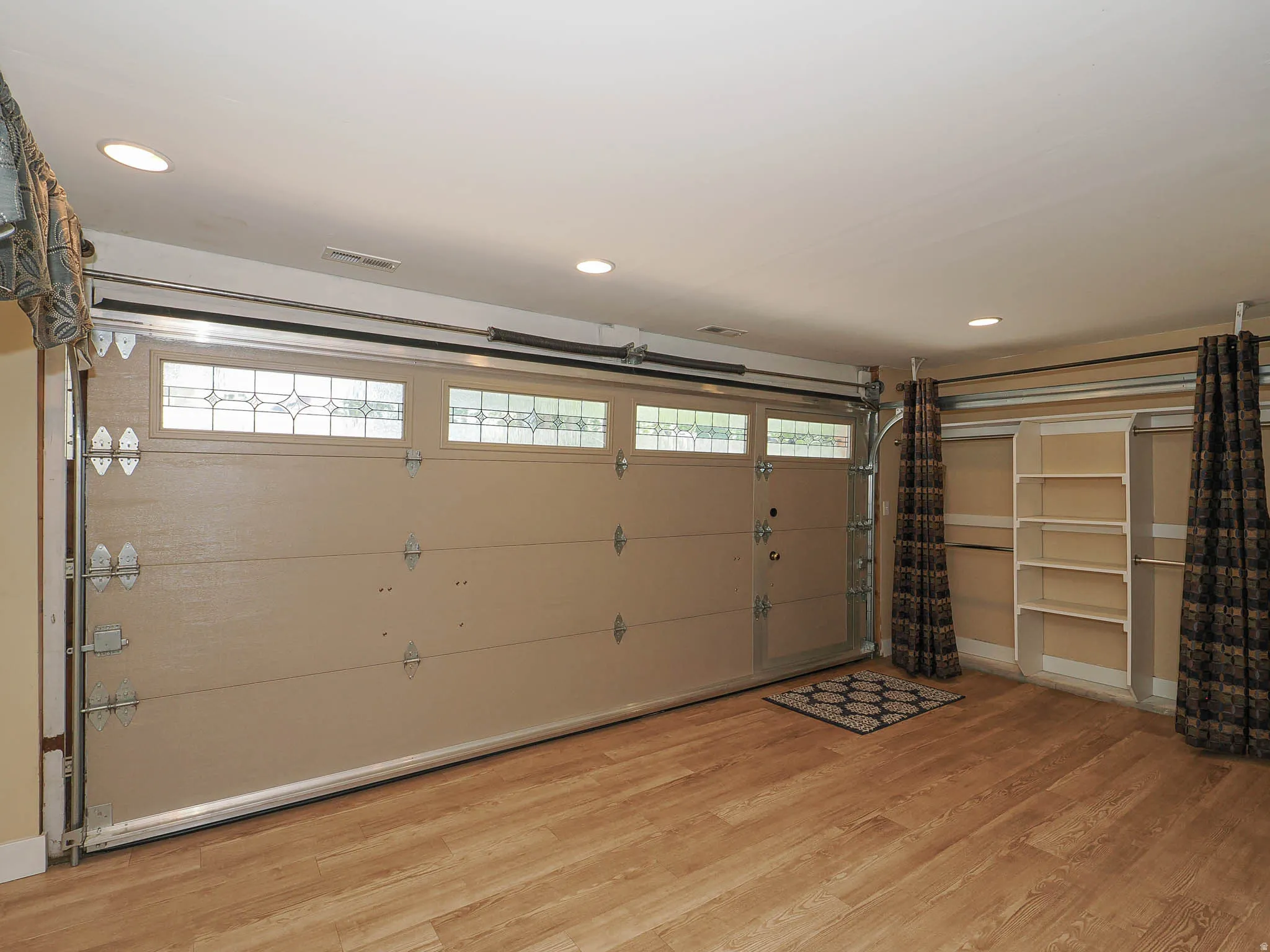 Finished room featuring wood-finish flooring, recessed lighting, and a garage door with decorative glass inserts