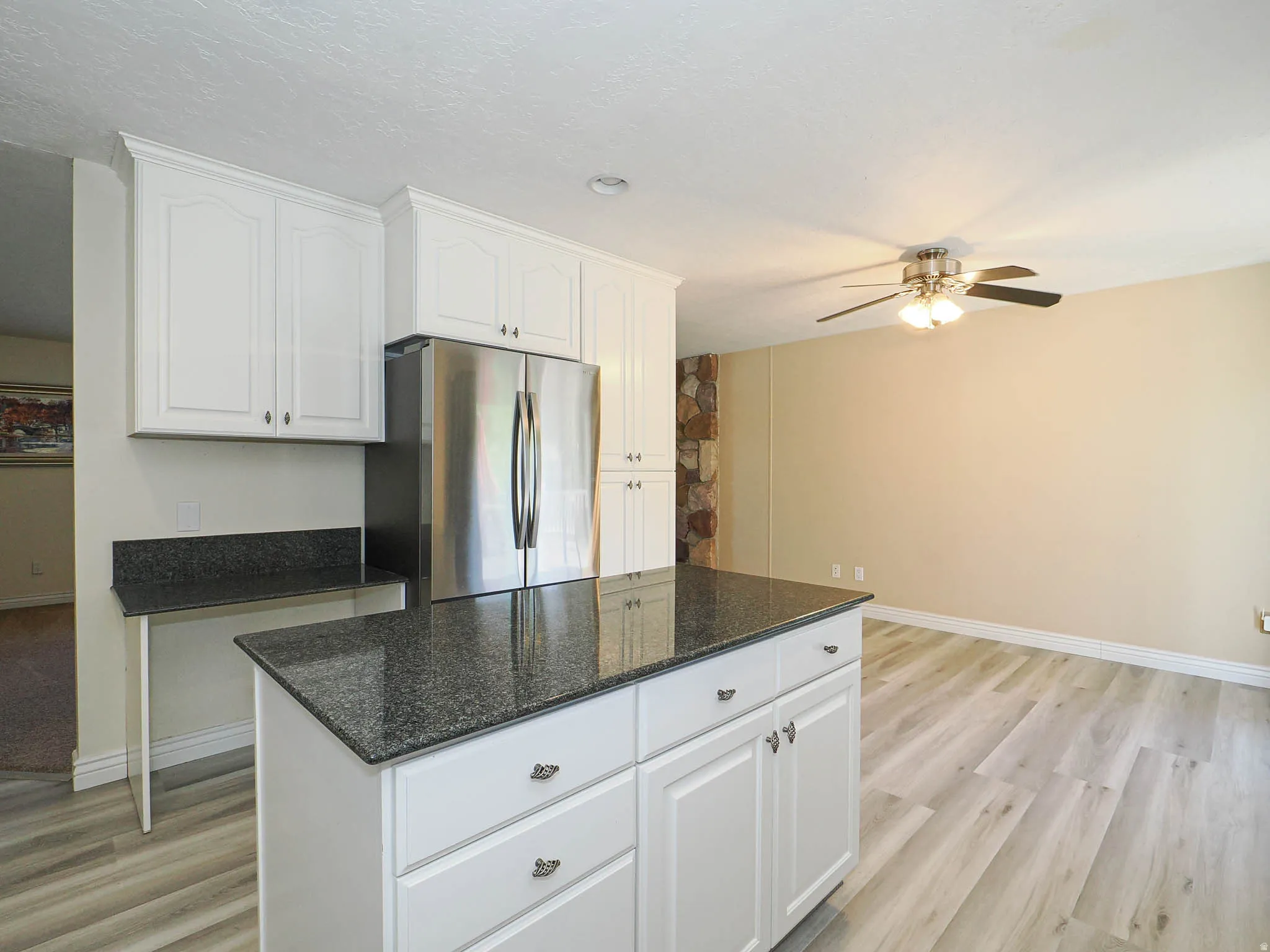Kitchen island featuring a dark granite countertop and white cabinetry with brushed nickel hardware