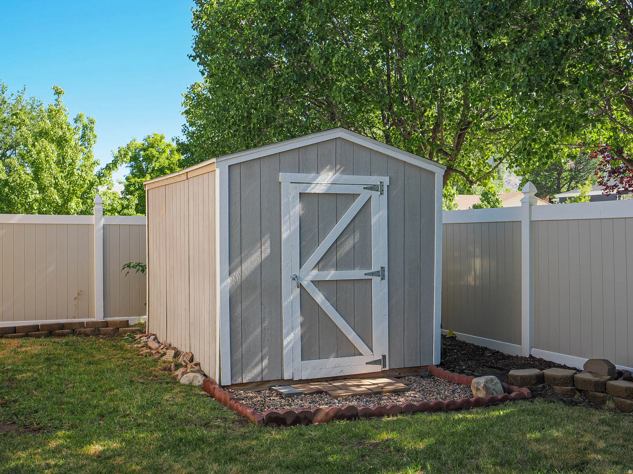 Storage shed with a gray finish and white trim, featuring a white barn-style door