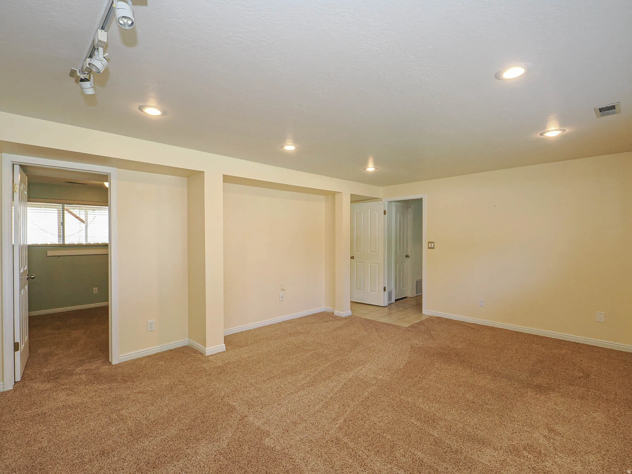 Spacious room featuring neutral carpeting and recessed lighting