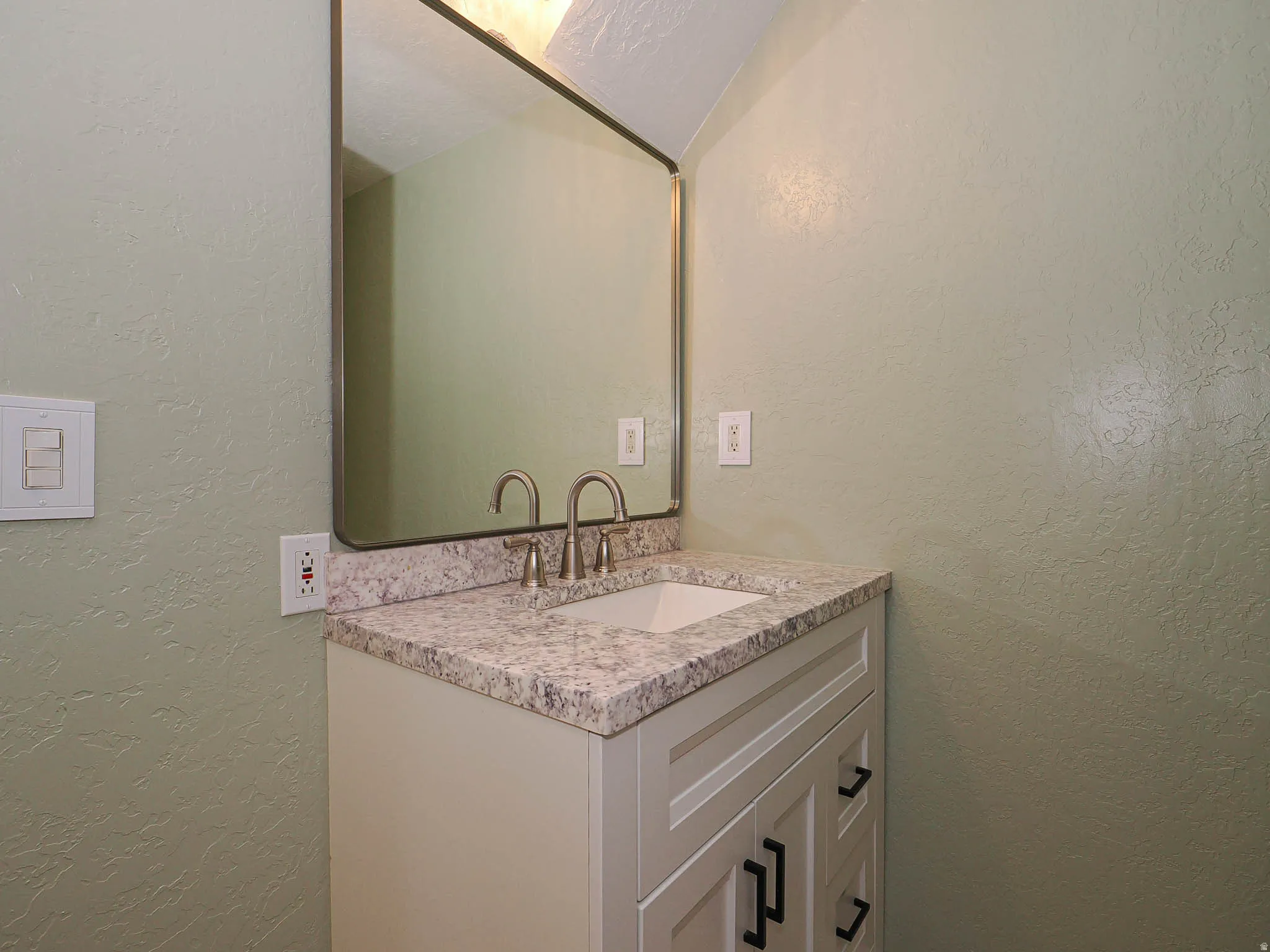 Contemporary vanity with a granite-style countertop, undermount sink, and brushed nickel faucet
