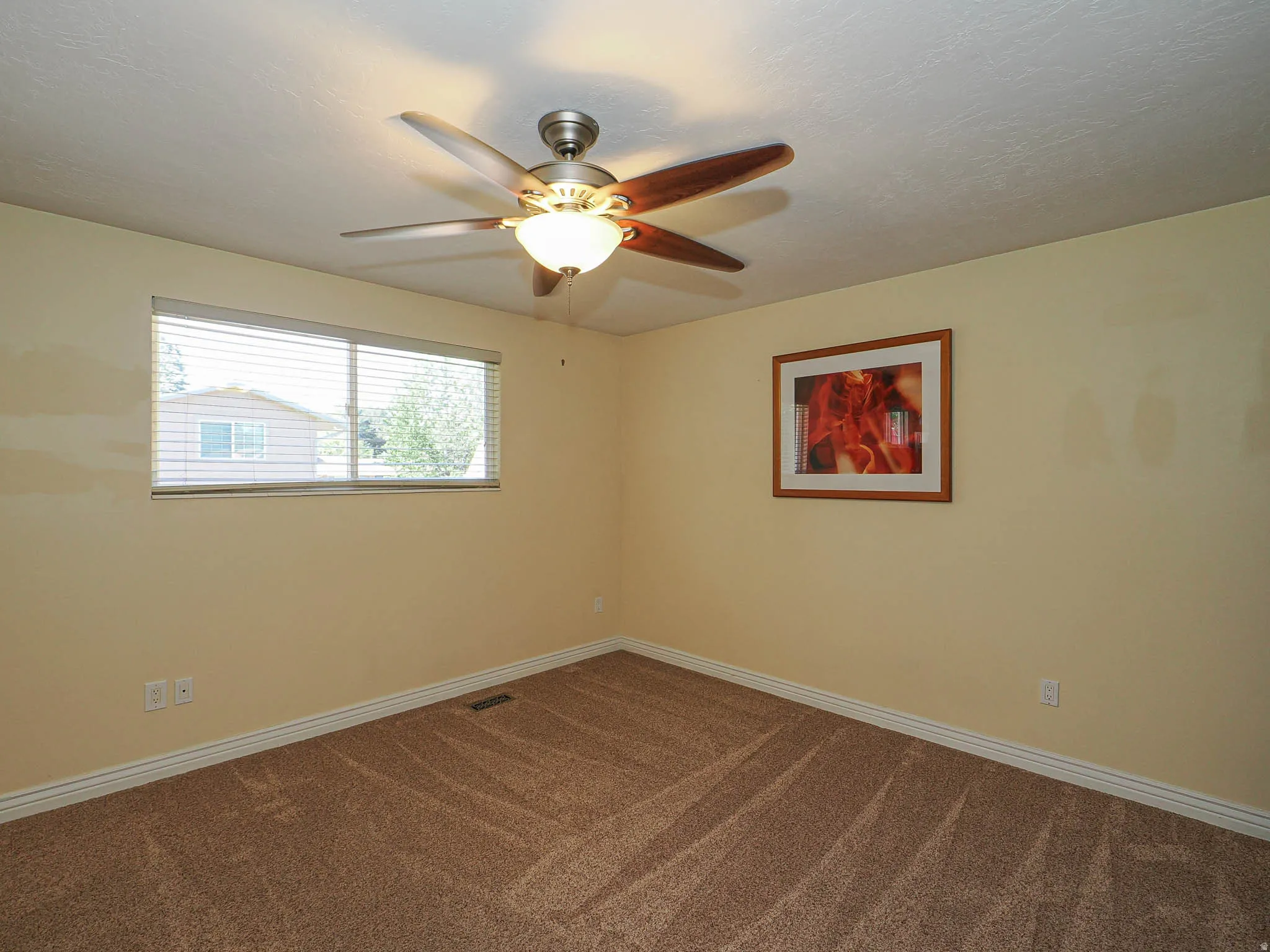 Carpeted room featuring a ceiling fan with light fixture, a window with horizontal blinds, white baseboards, and light-toned walls