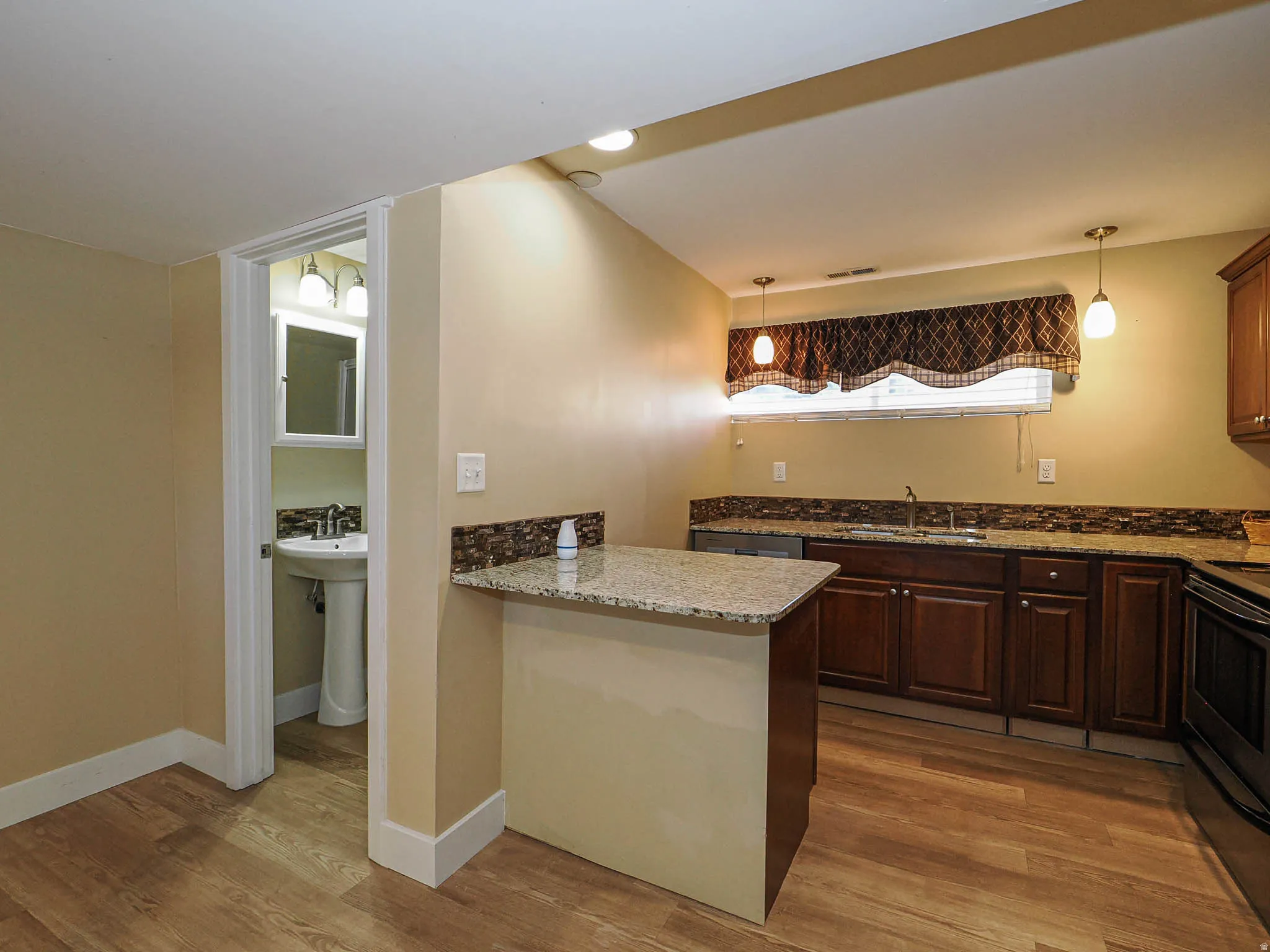 Kitchen featuring wood-finish flooring, dark wood cabinetry, and granite countertops
