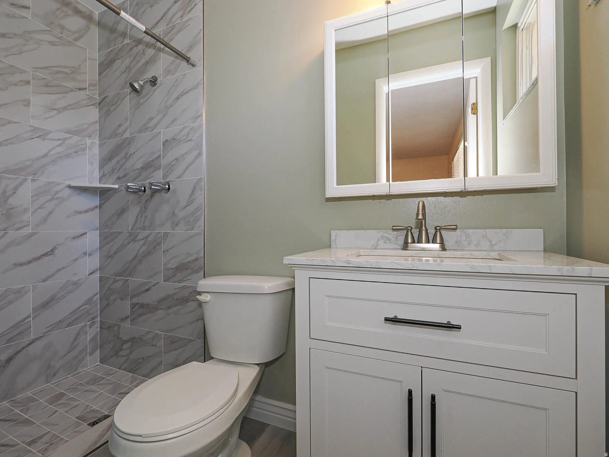 Bathroom featuring a white vanity with an integrated sink, brushed nickel faucet, and a wall-mounted mirrored medicine cabinet